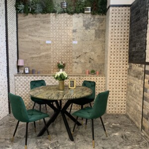 masă rotundă cu blat din granit natural și patru scaune din catifea verde, într-un spațiu decorat cu piatră naturală